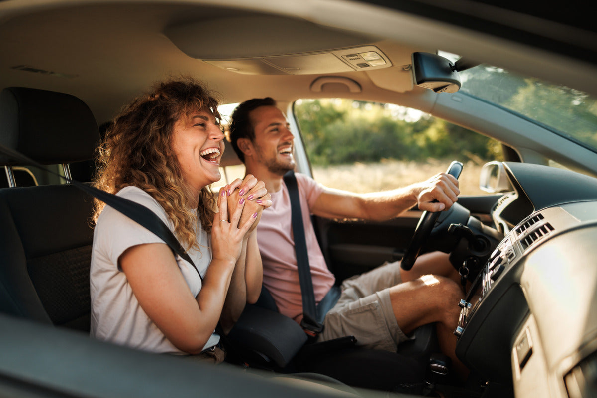 A couple sings along to the radio inside a car. 