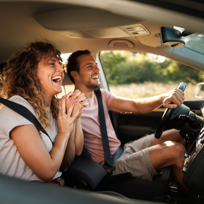 A couple sings along to the radio inside a car. 