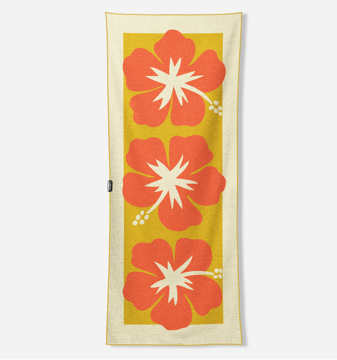 A rectangular beach towel with a cream border and a central yellow panel featuring three large orange-red hibiscus flowers with white centers, shown flat against a light gray background.