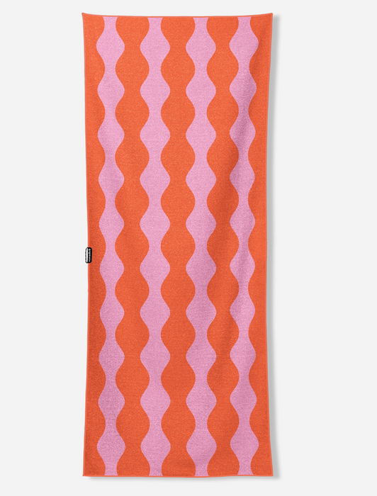 A rectangular knit scarf featuring a vertical wavy stripe pattern in vibrant orange and light pink, shown flat against a light gray background.