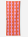 A rectangular knit scarf featuring a vertical wavy stripe pattern in vibrant orange and light pink, shown flat against a light gray background.