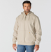 A man wearing a light beige Carhartt pullover hoodie with a half-zip neckline and drawstrings, paired with blue jeans, against a light gray studio background.