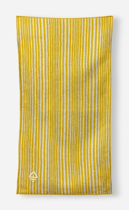 A yellow and white vertically striped fabric item, likely a towel or scarf, featuring a small white geometric logo near the bottom left, shown against a light gray background.