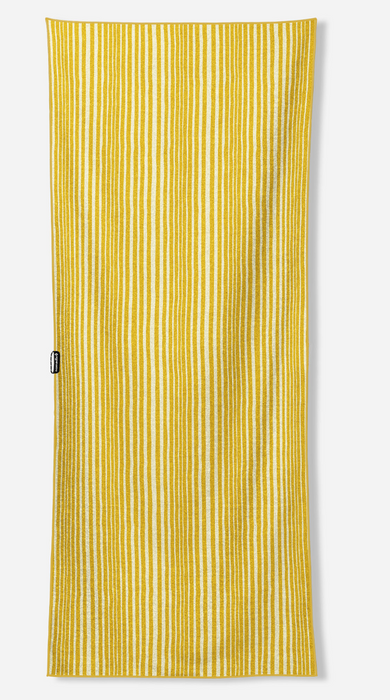 A yellow and white vertically striped cotton beach towel with a small black brand tag on the left side, shown against a light gray background.