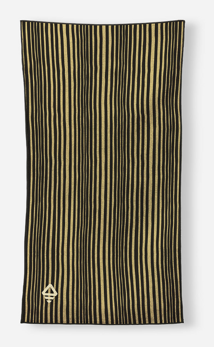 A rectangular scarf with vertical black and gold stripes, featuring a small gold geometric emblem in the bottom-left corner, displayed against a light gray background.