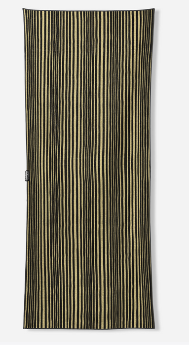 A rectangular textile item, likely a towel or blanket, featuring a vertical stripe pattern in black and warm beige, shown flat against a light gray background.