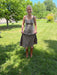 Woman standing in a grassy area wearing a dress and boots.