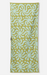 A long rectangular towel with a repeating abstract floral or starburst pattern in pale aqua on a muted yellow-green background, shown flat against a light gray studio background.