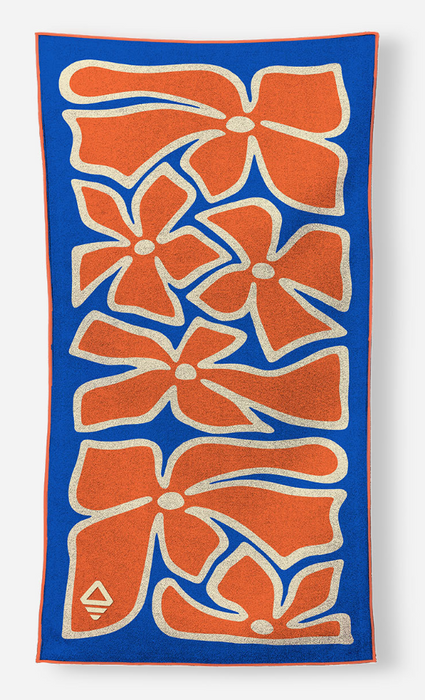 A rectangular blue towel with a bold pattern of orange flowers outlined in white, shown flat against a light gray background.